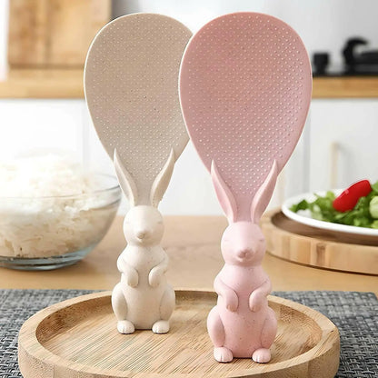 Rabbit spoon on table pink and white color with some rice on backside